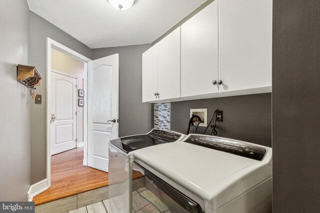 laundry room with cabinets, hardwood / wood-style floors, and washer and dryer