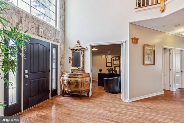 foyer entrance featuring a high ceiling, crown molding, and light hardwood / wood-style floors