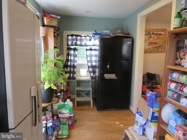 kitchen with light hardwood / wood-style floors and black refrigerator