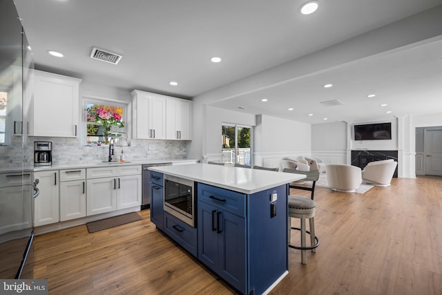 kitchen with a center island, white cabinetry, stainless steel microwave, and light hardwood / wood-style floors