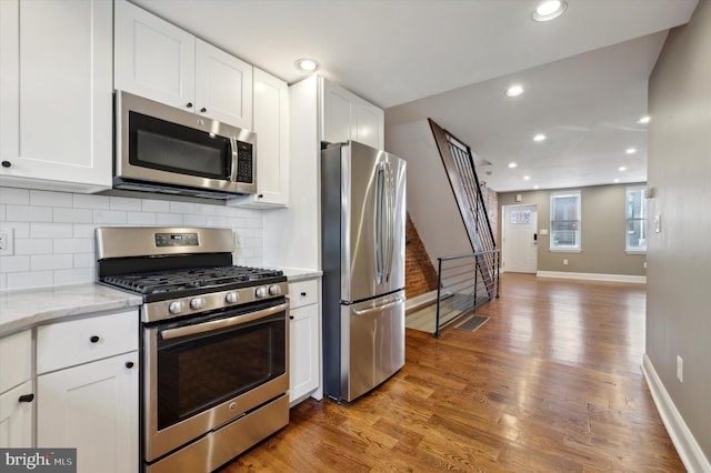 kitchen featuring decorative backsplash, stainless steel appliances, light stone countertops, dark hardwood / wood-style floors, and white cabinetry