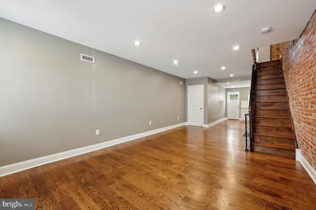 interior space with hardwood / wood-style floors and brick wall