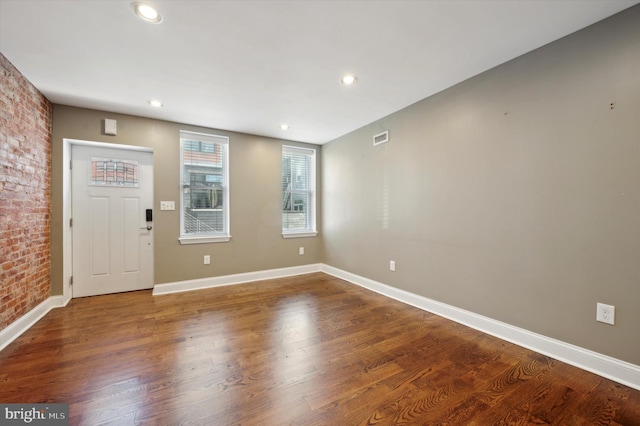 entrance foyer featuring wood-type flooring and brick wall