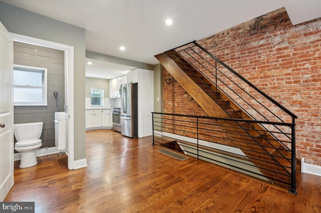 interior space with wood-type flooring and brick wall