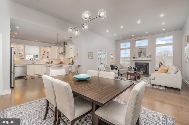 dining room with ceiling fan with notable chandelier, sink, and hardwood / wood-style floors