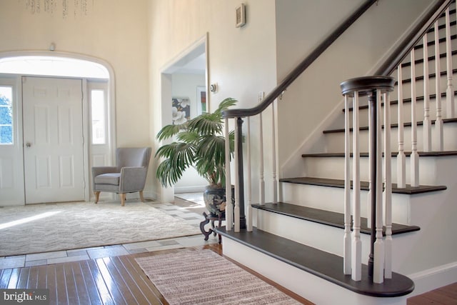 foyer with hardwood / wood-style flooring and a towering ceiling