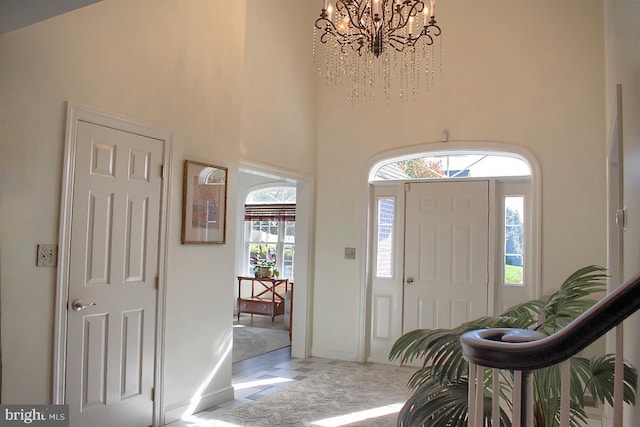 entrance foyer with a wealth of natural light, a chandelier, and a towering ceiling