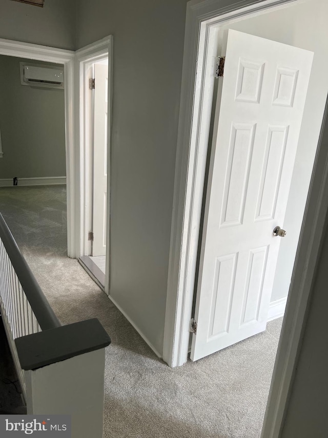 corridor with a wall mounted AC and light colored carpet