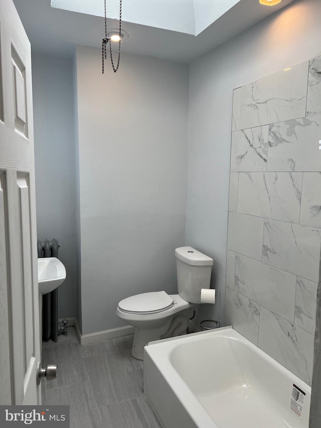 bathroom featuring a bathtub, a skylight, and toilet