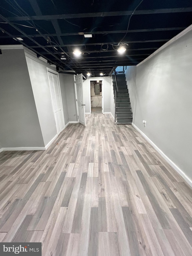 basement featuring electric panel and light hardwood / wood-style floors