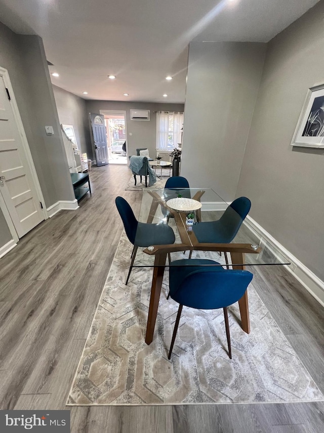 dining area with a wall mounted air conditioner and hardwood / wood-style floors