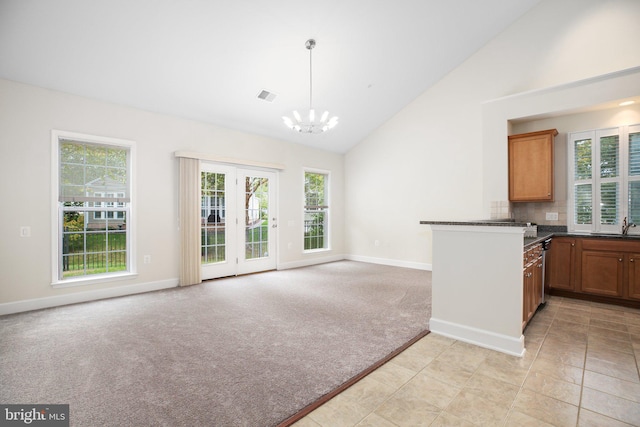 kitchen featuring sink, an inviting chandelier, decorative light fixtures, high vaulted ceiling, and light colored carpet