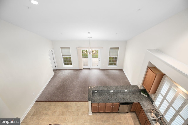 unfurnished living room featuring a chandelier and light colored carpet