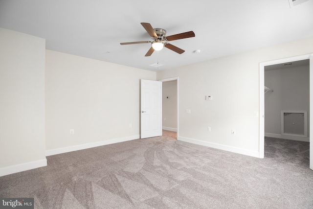 unfurnished bedroom featuring ceiling fan, light carpet, a closet, and a spacious closet