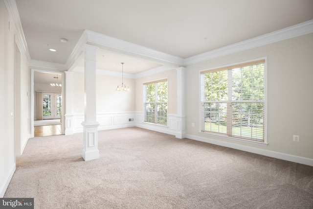 spare room featuring light carpet, crown molding, decorative columns, and an inviting chandelier