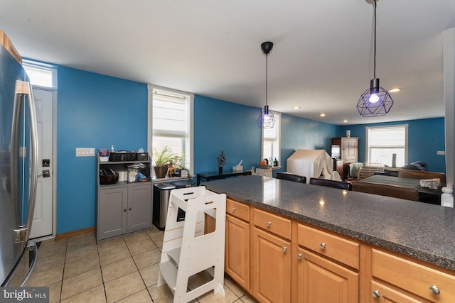 kitchen with stainless steel refrigerator, light tile patterned floors, and hanging light fixtures