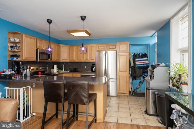 kitchen with light hardwood / wood-style floors, kitchen peninsula, and stainless steel appliances