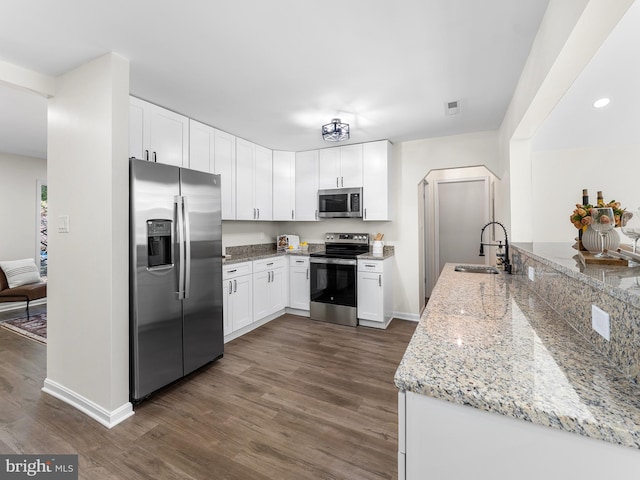 kitchen with dark wood-type flooring, white cabinets, sink, light stone countertops, and stainless steel appliances