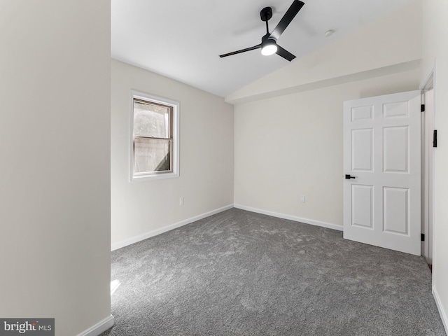 spare room with ceiling fan, dark carpet, and vaulted ceiling