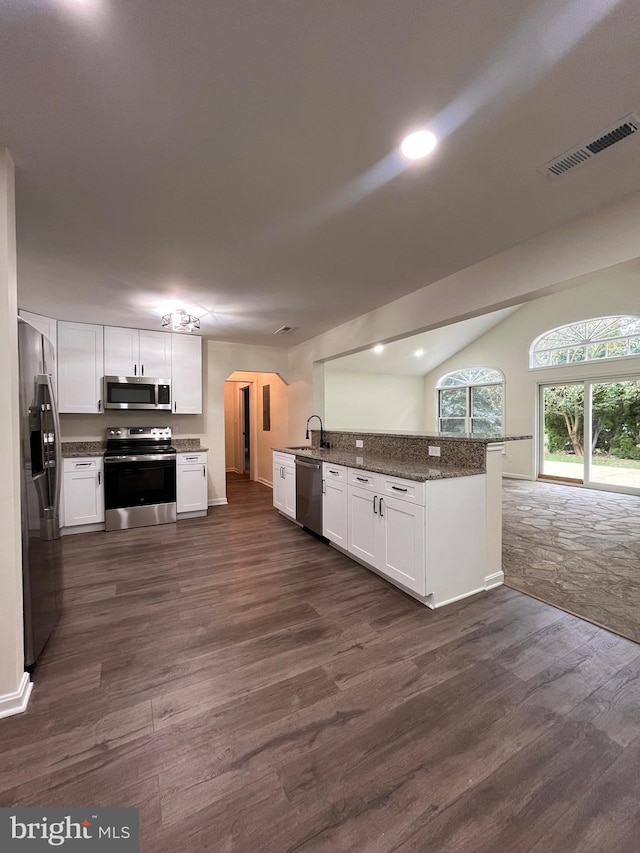 kitchen featuring kitchen peninsula, dark hardwood / wood-style flooring, stainless steel appliances, and white cabinetry