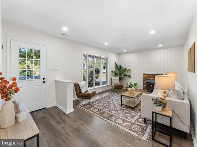 living room with plenty of natural light, a fireplace, dark wood-type flooring, and wooden walls