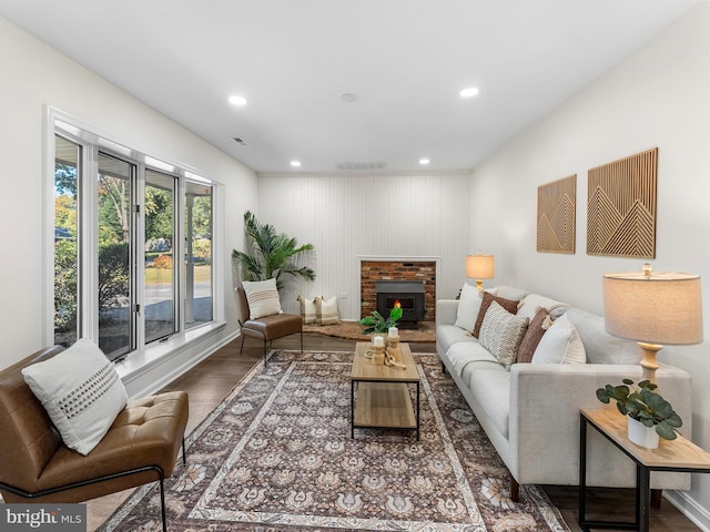 living room with wood-type flooring, a brick fireplace, and wood walls