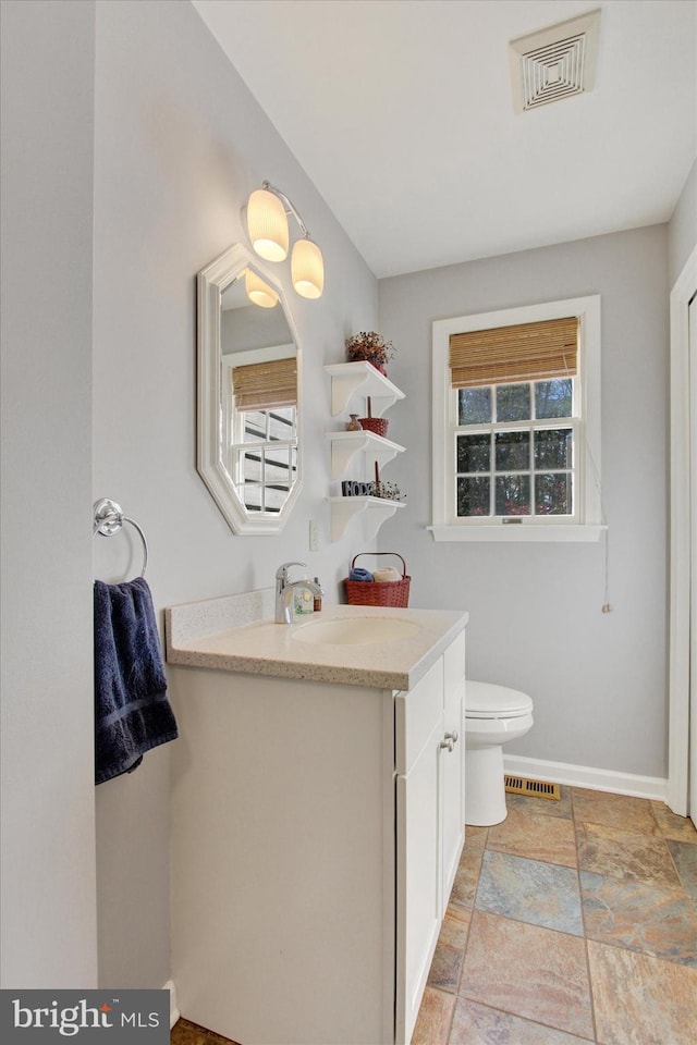 bathroom with plenty of natural light, vanity, and toilet