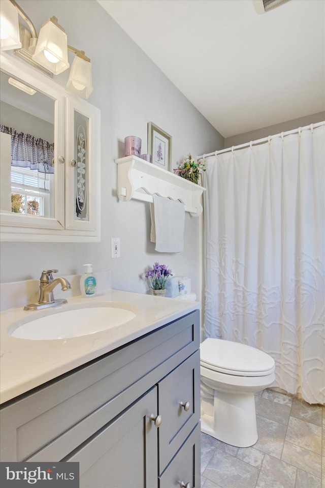 bathroom with walk in shower, vanity, and toilet