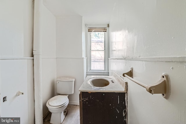 bathroom with toilet, vanity, and tile patterned flooring