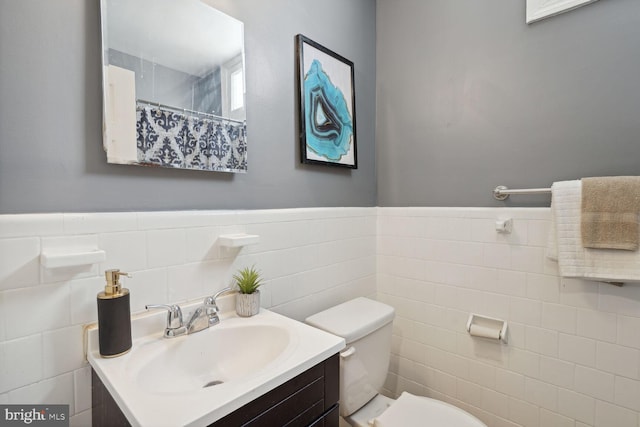 bathroom with tile walls, vanity, a shower with shower curtain, and toilet