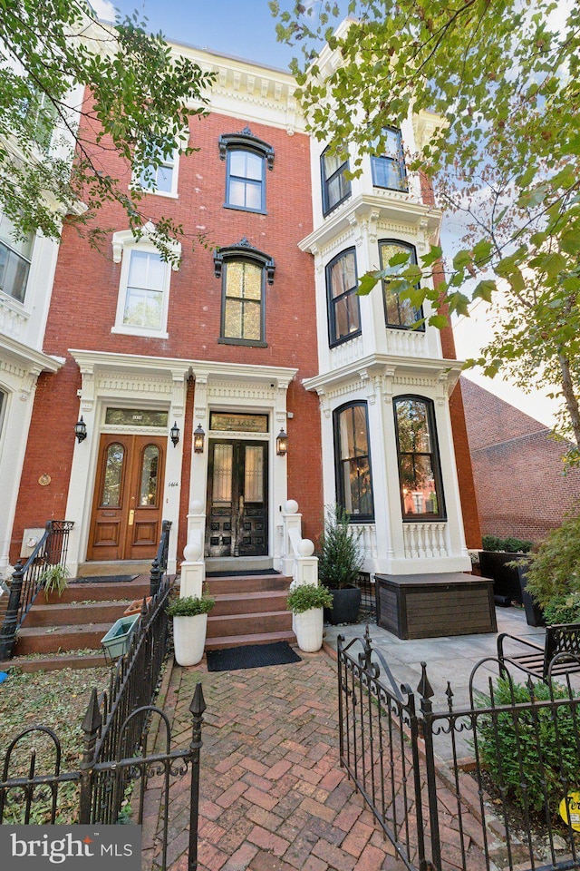 view of front of property featuring french doors, brick siding, and a fenced front yard