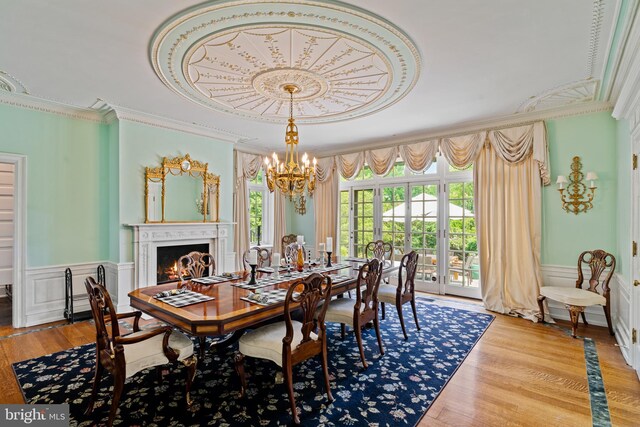 dining area with wood-type flooring, a notable chandelier, and crown molding