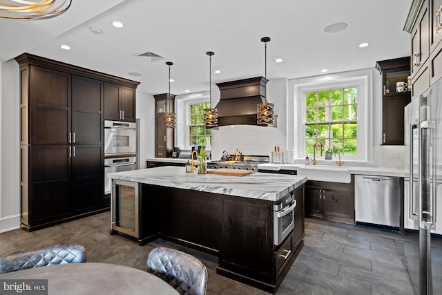 kitchen with a center island, stainless steel appliances, tasteful backsplash, premium range hood, and pendant lighting