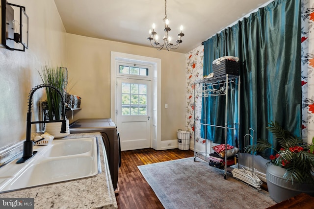 washroom featuring washing machine and dryer, a notable chandelier, sink, and dark hardwood / wood-style flooring