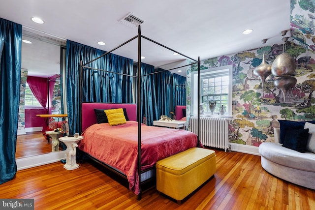 bedroom featuring multiple windows, radiator, and wood-type flooring