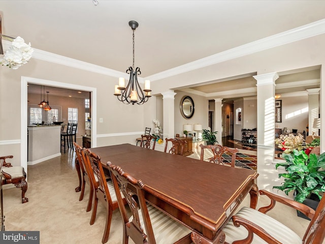 dining room with a chandelier, carpet flooring, decorative columns, and crown molding