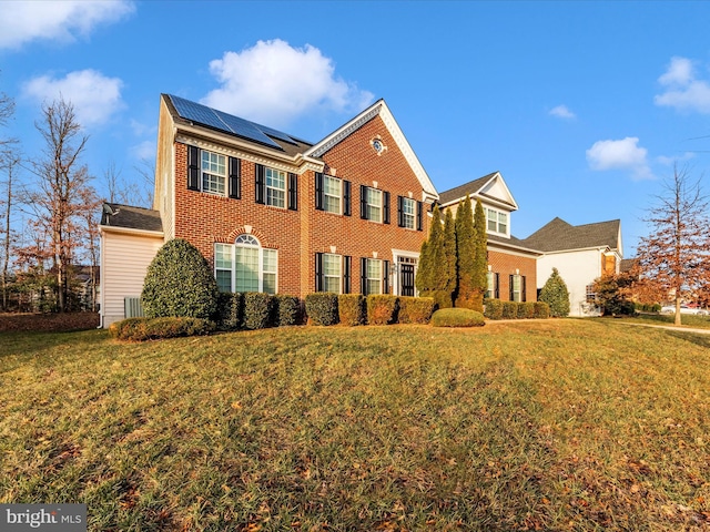 view of front of home with a front yard and solar panels