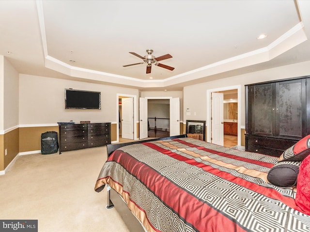 bedroom featuring ensuite bathroom, ceiling fan, and a raised ceiling