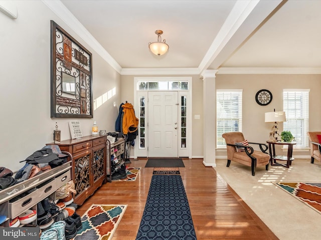 entrance foyer featuring wood-type flooring, crown molding, and ornate columns