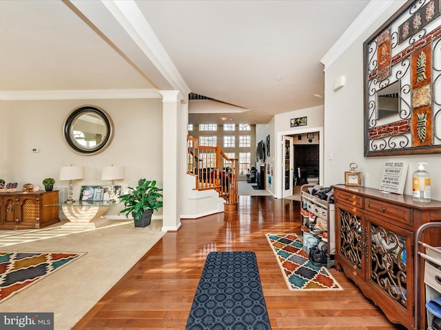 entrance foyer featuring decorative columns, crown molding, and hardwood / wood-style floors