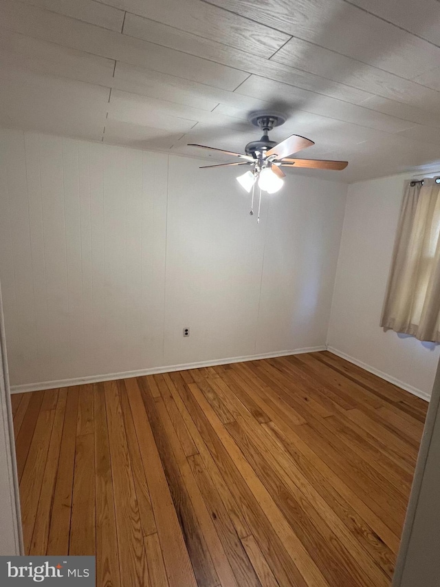 empty room featuring baseboards, a ceiling fan, and hardwood / wood-style floors