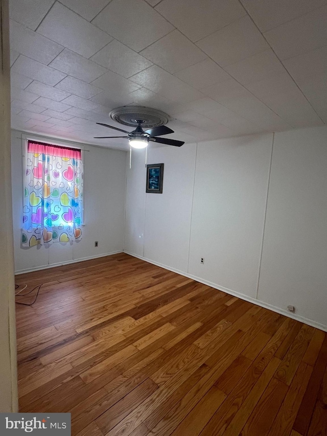 unfurnished room with baseboards, a ceiling fan, and wood finished floors