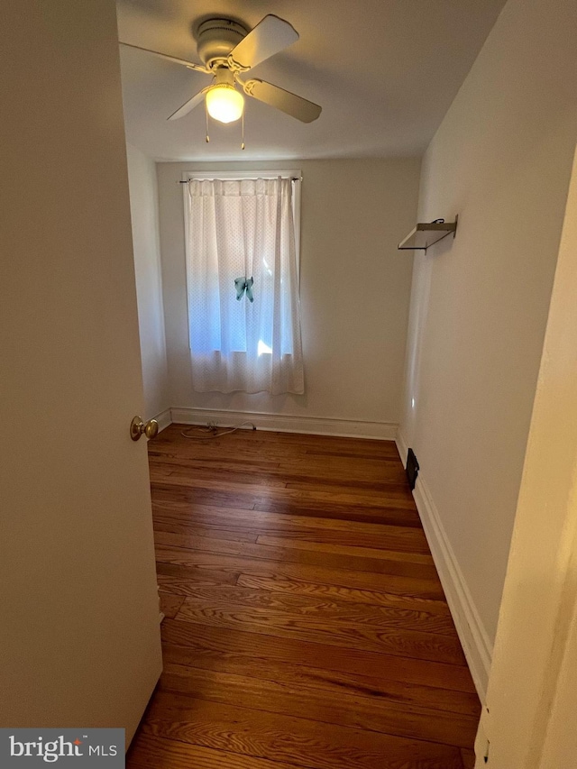 empty room with baseboards, a ceiling fan, and wood finished floors