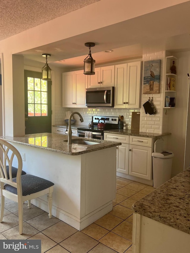 kitchen featuring backsplash, white cabinetry, stainless steel appliances, pendant lighting, and light tile patterned floors