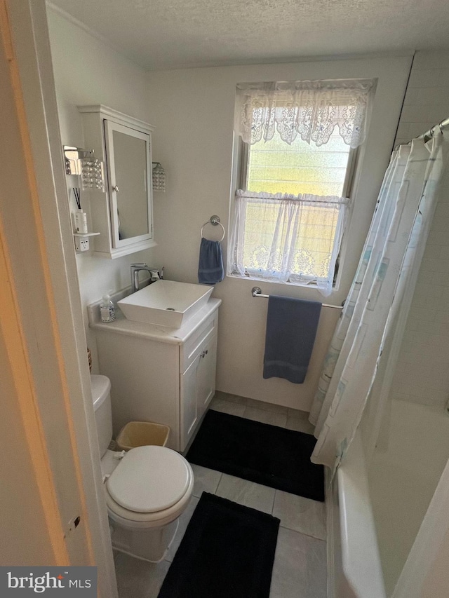 full bathroom featuring a textured ceiling, toilet, shower / bath combo with shower curtain, tile patterned flooring, and vanity