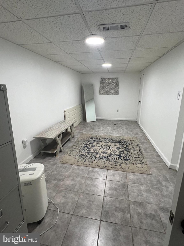 interior space with baseboards, visible vents, tile patterned floors, and a drop ceiling