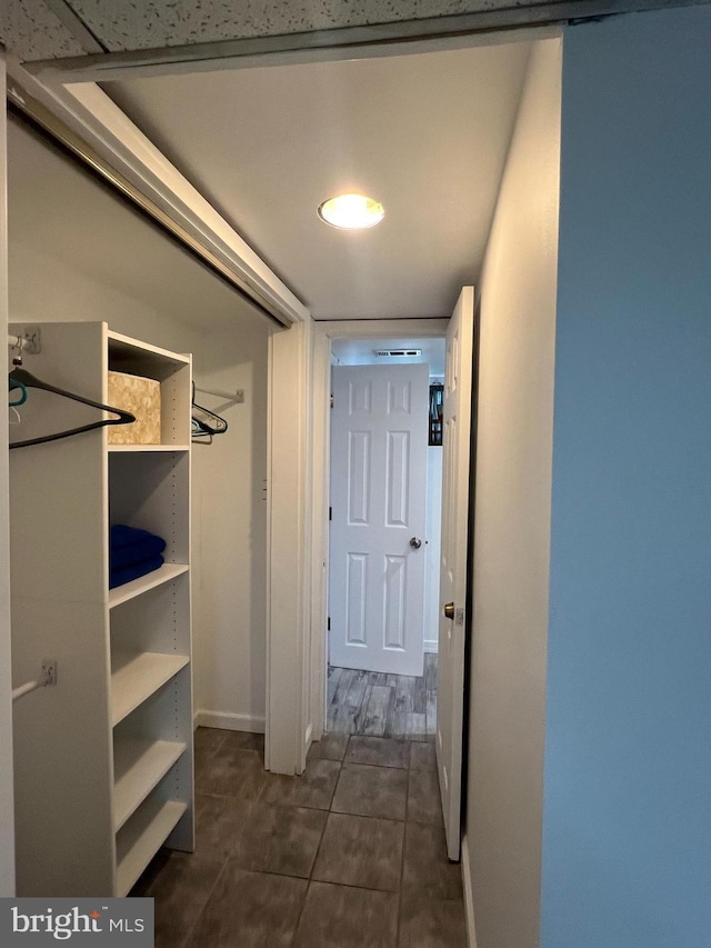 corridor featuring baseboards and dark tile patterned floors
