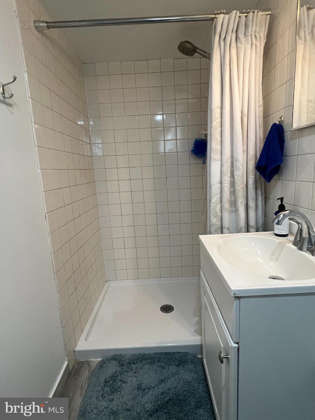 full bath featuring baseboards, vanity, and a shower stall