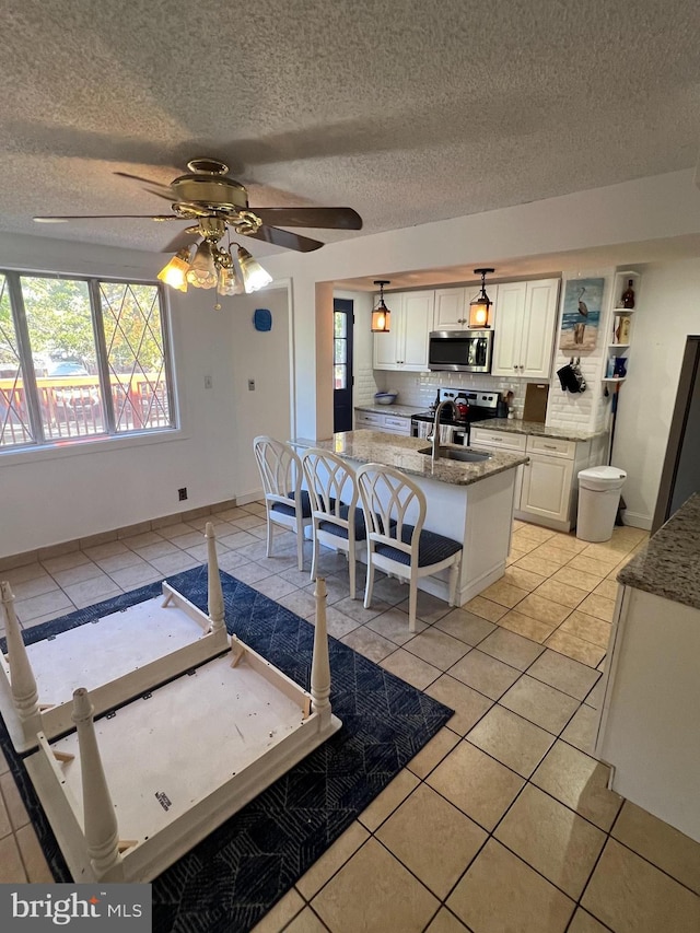 dining room with a textured ceiling, a healthy amount of sunlight, a ceiling fan, and light tile patterned floors