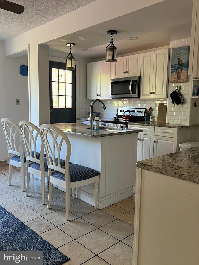 kitchen featuring light tile patterned flooring, decorative backsplash, decorative light fixtures, and white cabinets